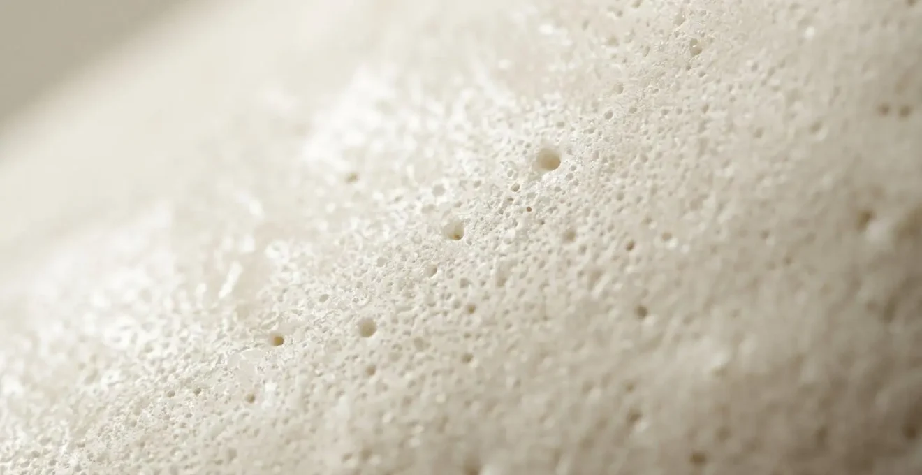 Extreme close-up of 19th-century soft-paste porcelain glaze showing microscopic porosity and light-scattering properties
